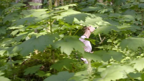 slow motion of young woman running in green forest on sunny summer day