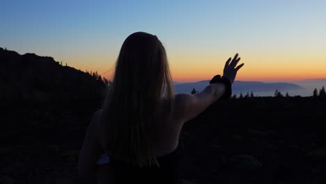 young mother with child on her hands wave for sunrise in mountain landscape