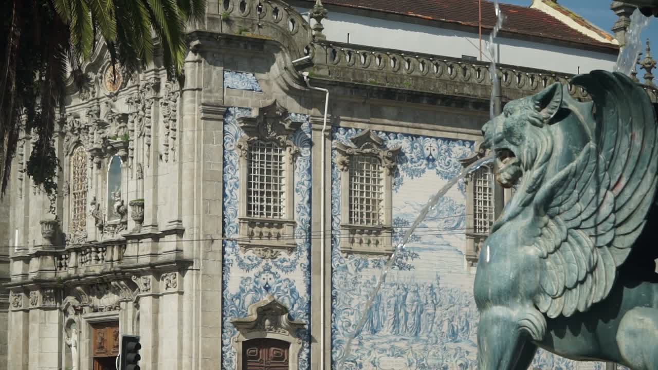 Truck Shot, Scenic view of the Winged Lion Fountain in town Square of Porto, Revealing Church Igreja do Carmo