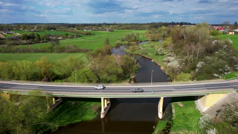 Drone-Dolly-Shot-Backward-from-Old-Bridge-with-Cars-and-Pedestrians-in-Łęczna,-Poland,-Sunny-Day