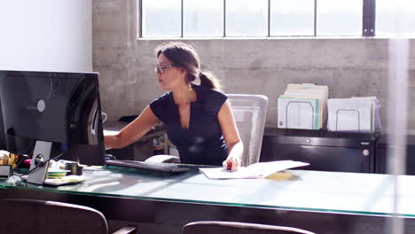 joven mujer de negocios ocupada comprobando papeles en su oficina