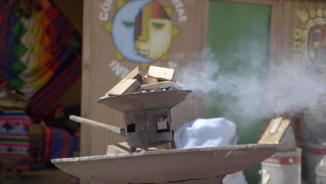 Slow-motion-shot-of-outdoor-Bolivian-fireplace-in-La-Paz,-Bolivia-with-color-house-in-background