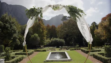 Wedding-arch-with-decorations-in-sunny-summer-garden-with-swimming-pool,-in-slow-motion