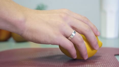 Man's-hand-puts-the-yellow-lemon-on-the-gray-table-on-white-background-with-fruits-closeup-slow-motion