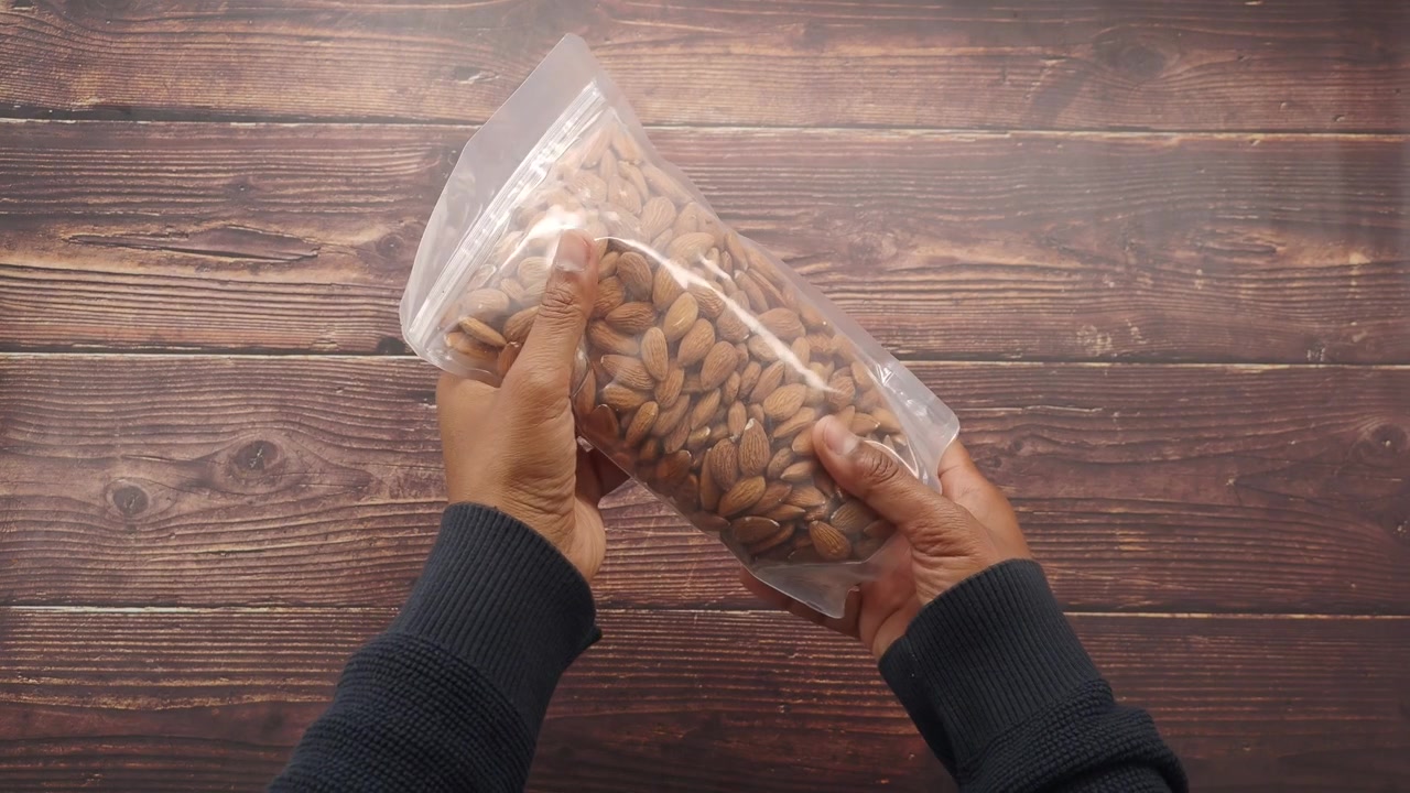 Person Holding a Clear Plastic Bag Filled with Almonds