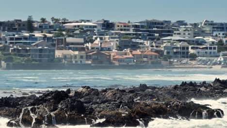 Toma-Ampliada-De-Drones-De-Las-Rocas-Frente-A-Big-Bay-Durante-La-Marea-Baja,-Con-Olas-Golpeándolas