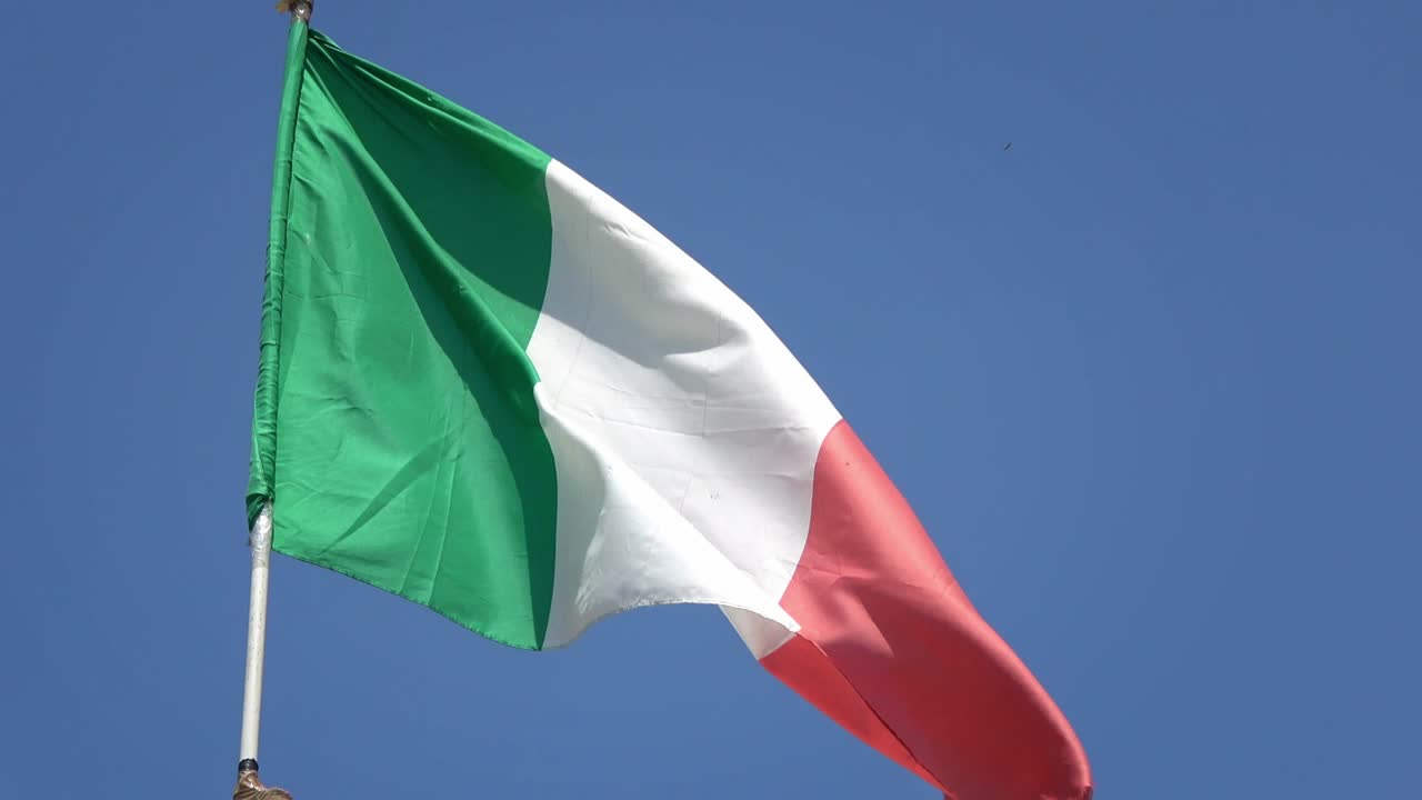 4K. Bandiera nazionale italiana che sventola al vento su un cielo blu. Bandiera italiana