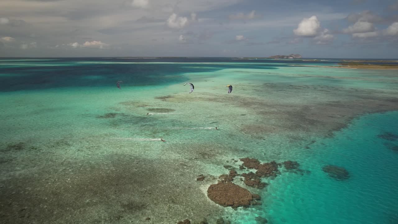 los kitesurfistas se deslizan sobre las aguas turquesas y los arrecifes de coral, vista aérea, los rocas