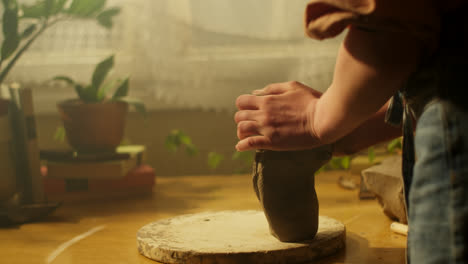 mujer moldeando arcilla en una rueda de alfareros