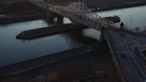 aerial rise over looking over the harlem river of nyc and a gorgeous bridge and the fdr drive at sunrise.  sun rises over the south bronx with a lens flare.  camera tilts down.