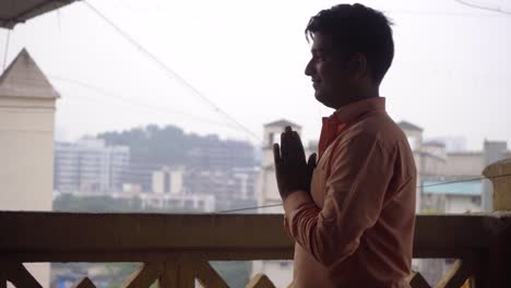 An-Indian-man-in-formals-doing-namaste-Mumbai-city-line-in-the-background