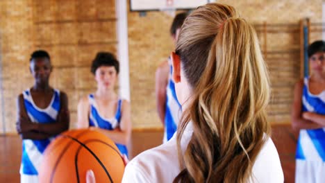 entrenador instruyendo a un estudiante en la cancha de baloncesto