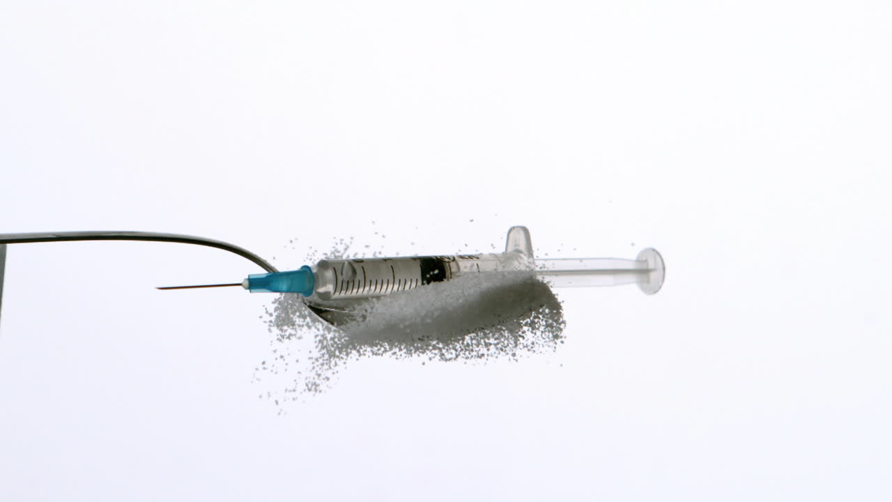 Syringe falling onto spoon of sugar