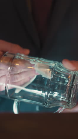 bartender wipes glass mug standing at counter in pub closeup. barman cleans beer cup preparing to serve guests in brewery. restaurant employee