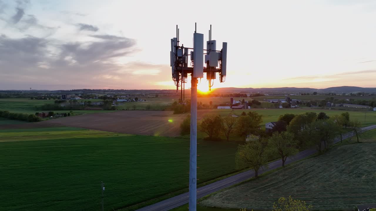 Aerial orbit of communication tower in american countryside. Rural street beside small town and agricultural farm fields in midwest of Amerikas. Wide shot.