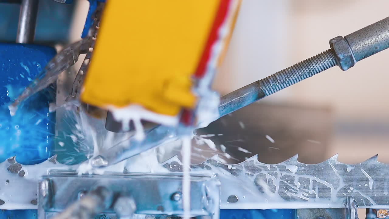 la máquina afila los dientes de la sierra de banda en chorros de agua fría en la planta
