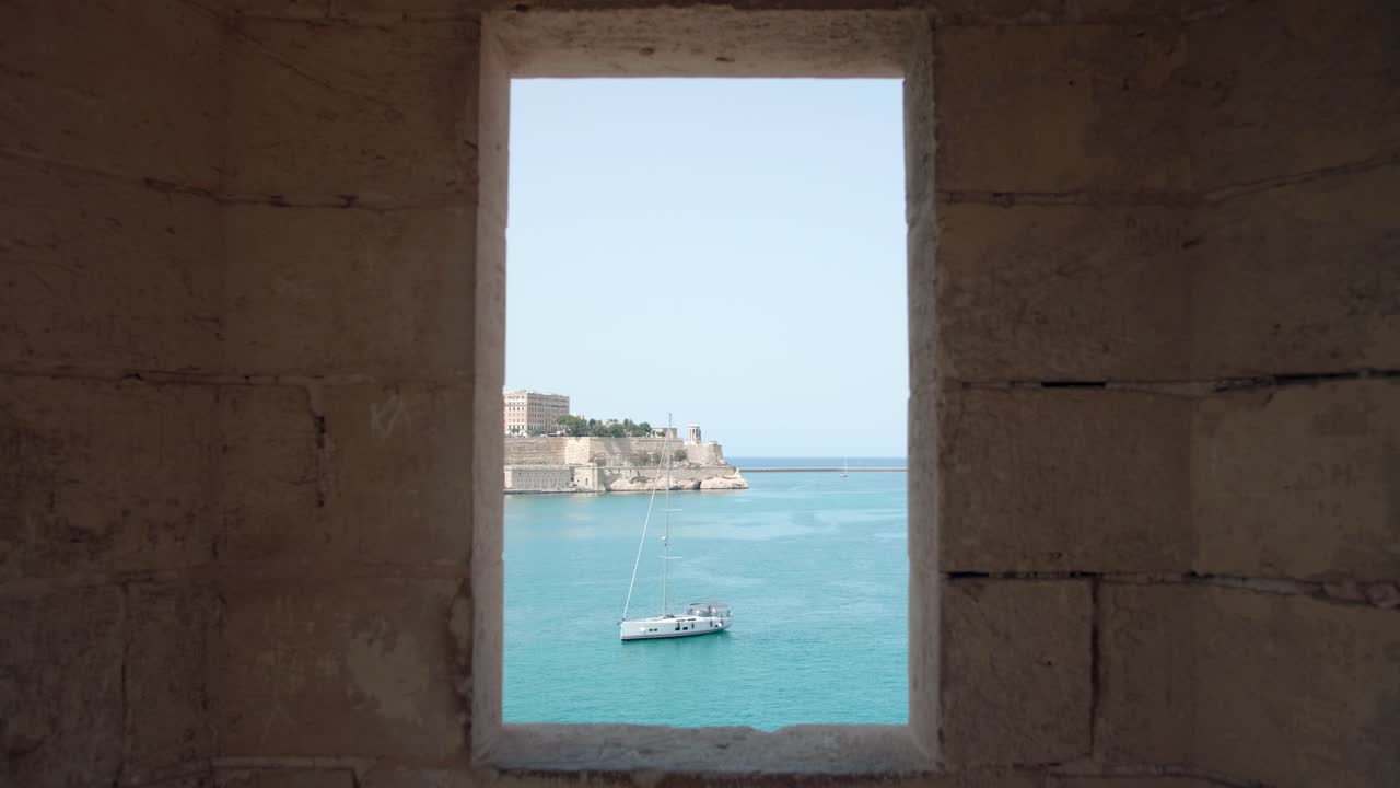 vista de la ciudad medieval con costa marina y barco turístico a través del marco de la ventana - tiro estático
