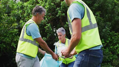 caucasian multi generation group of male and female volunteers picking up litter in a field