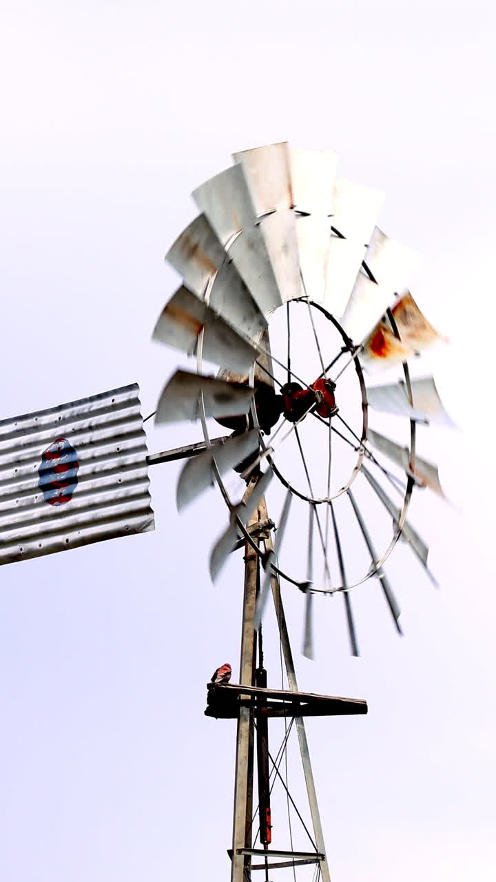 Vertical slow motion of old rusty windmill rotating in open countryside