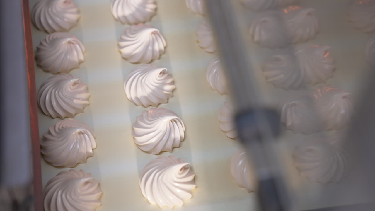 Freshly-made vanilla zephyr desserts on the conveyor line. Marshmallow manufacturing at modern food factory. Close up. Top view.