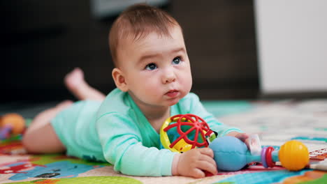 adorable toddler being busy looking at his toys. lovely baby boy looking up and then turning to his toys again. blurred backdrop.