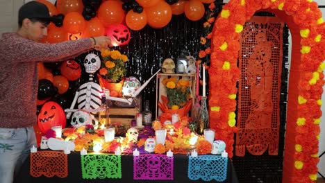 hombre esparciendo flores de cempasuchil en el altar decorado del día de los muertos