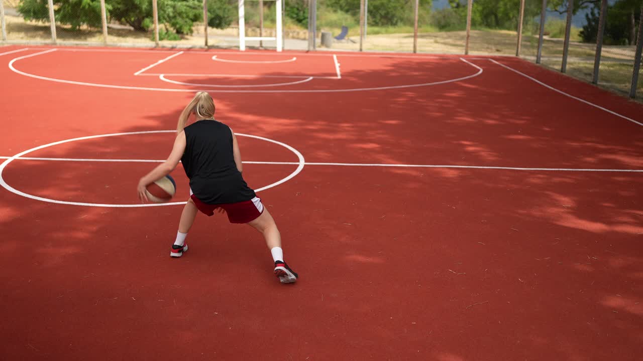 mujer jugando al baloncesto en la cancha al aire libre