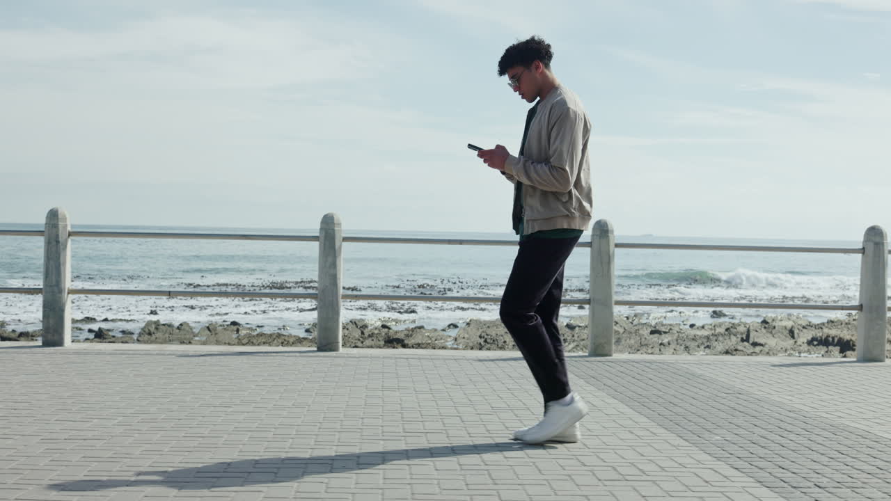 Man walking with a phone on the coast