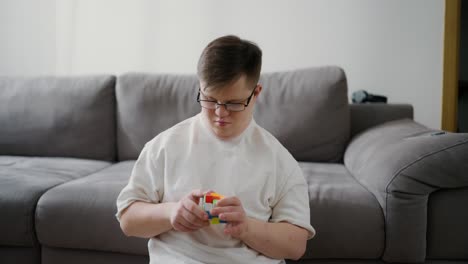 down syndrome man sitting on floor at home and playing with rubik cube