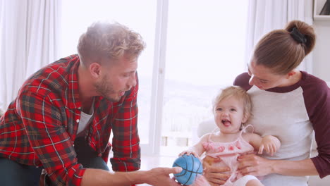 young parents and toddler daughter playing in sitting room