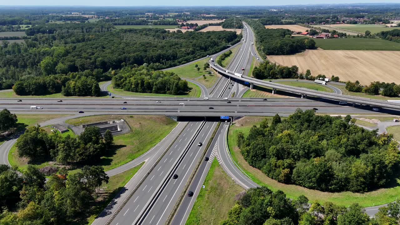 German Autobahn motorway freeway junction on sunny summer day. Aerial establishing wide shot. Traffic scene on elevated interchange in European suburb. Green trees in beautiful day