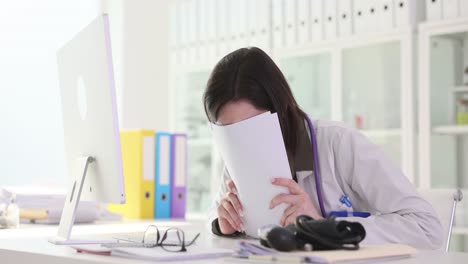female doctor overwhelmed by paperwork in her office