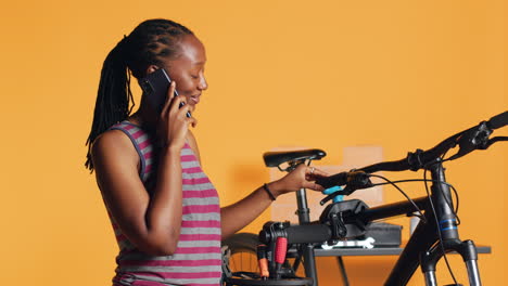 Woman-talking-on-phone-with-technician,-asking-for-help-on-fixing-defective-bike