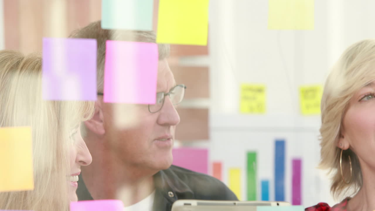  Businessman writing on post it with his colleagues