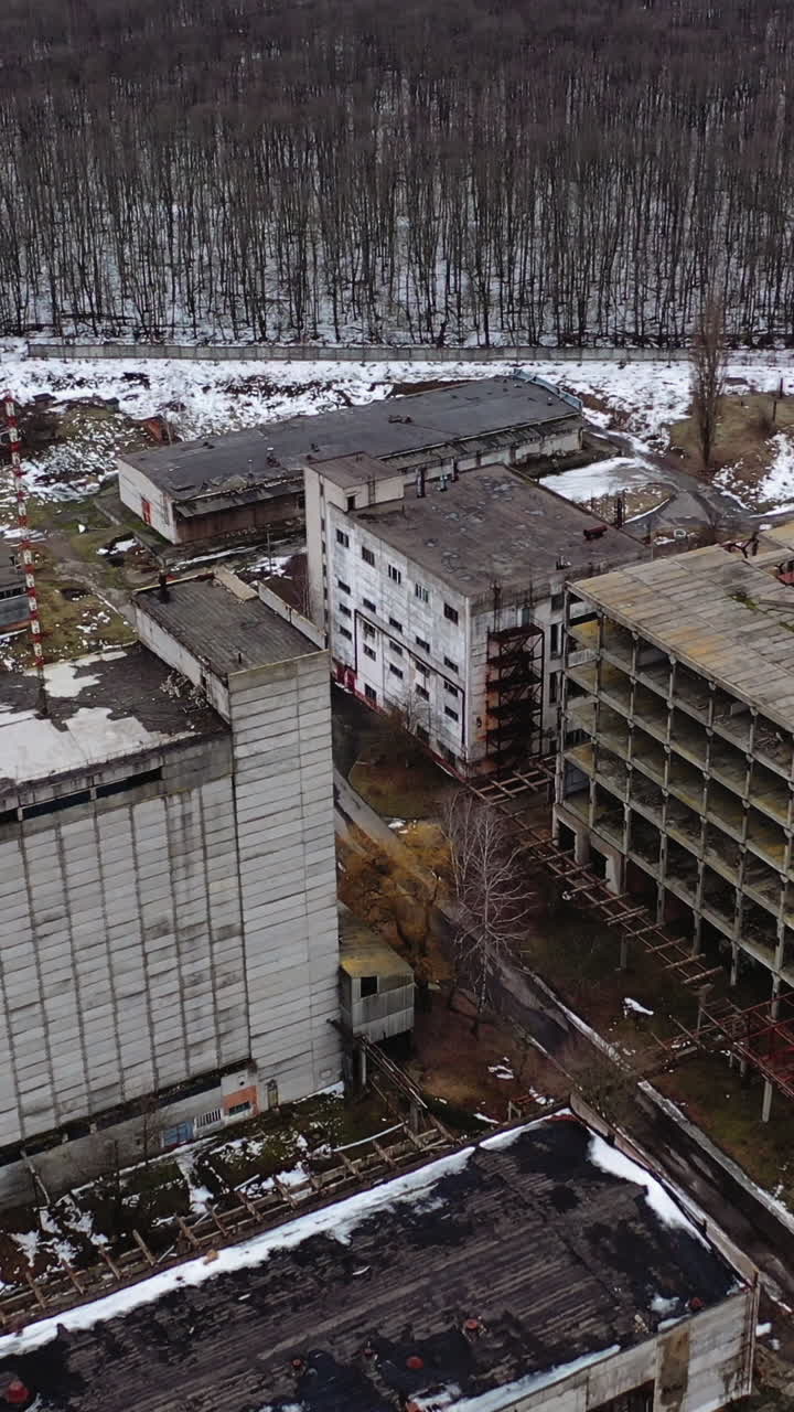 Damaged industrial plant. Old factory with abandoned buildings. Desolate place after the military actions. View from above. Vertical video