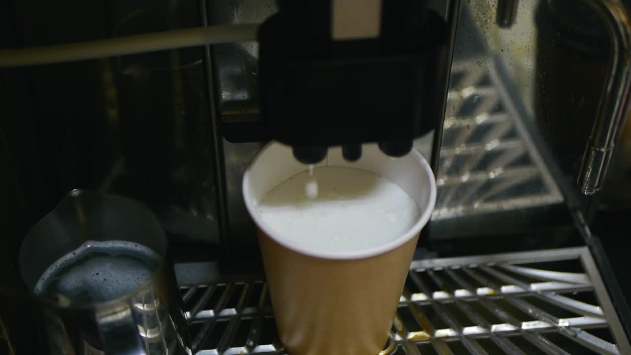 Overhead shot of coffee barista machine dripping milk and coffee into brown paper cup