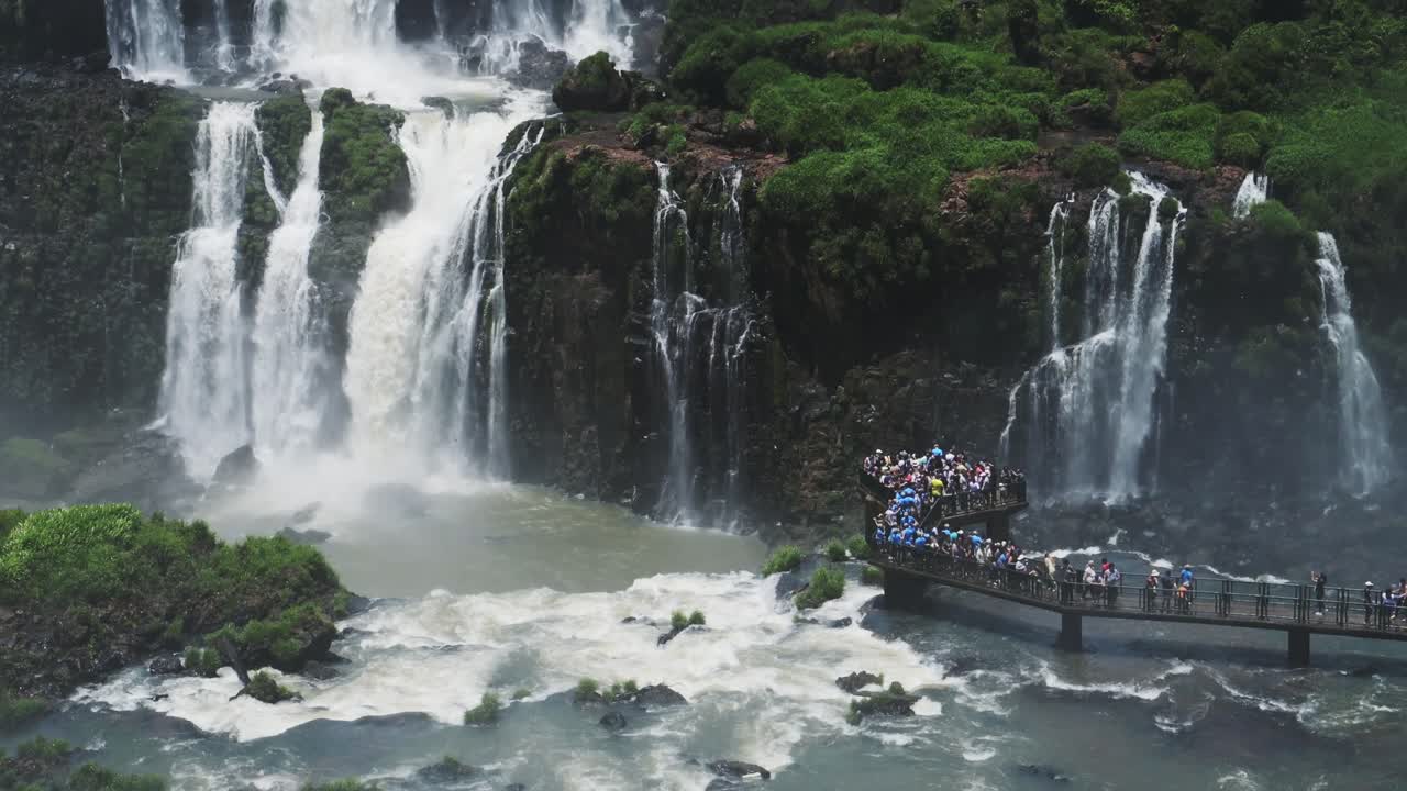 이구아즈 폭포 (iguazu falls) 는 브라질의 관광 명소로, 멋진 슬로모션으로 내려다보는 플랫폼에서 보는 거대한 폭포로, 사람들이 지켜보는 동안 충돌하고 어지는 모습을 보여준다.