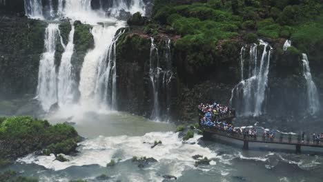 cataratas de iguazu en brasil, increíble destino turístico vista desde la plataforma mirando sobre hermosa cámara lenta cayendo enormes cascadas chocando y salpicando en la gente que mira