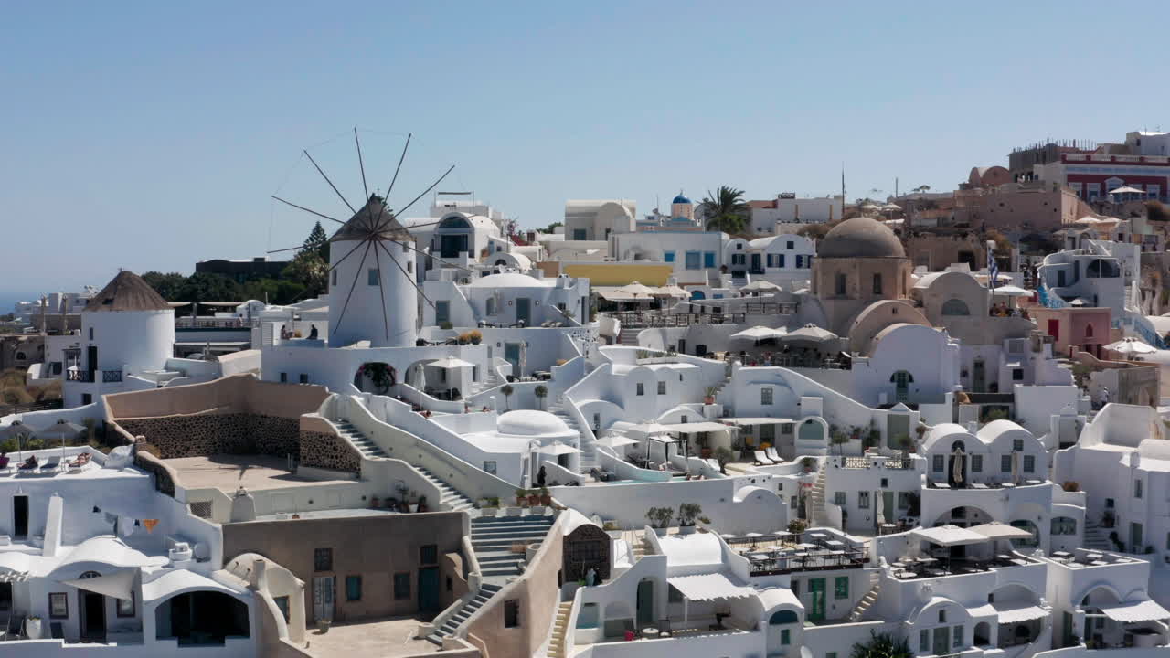 famoso molino de viento de oia y típica casa pintada de blanco y azul en santorini, grecia