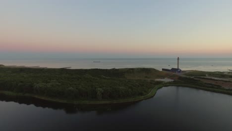 antena: el muelle, la playa y el faro durante la puesta de sol cerca del pueblo de westkapelle, países bajos