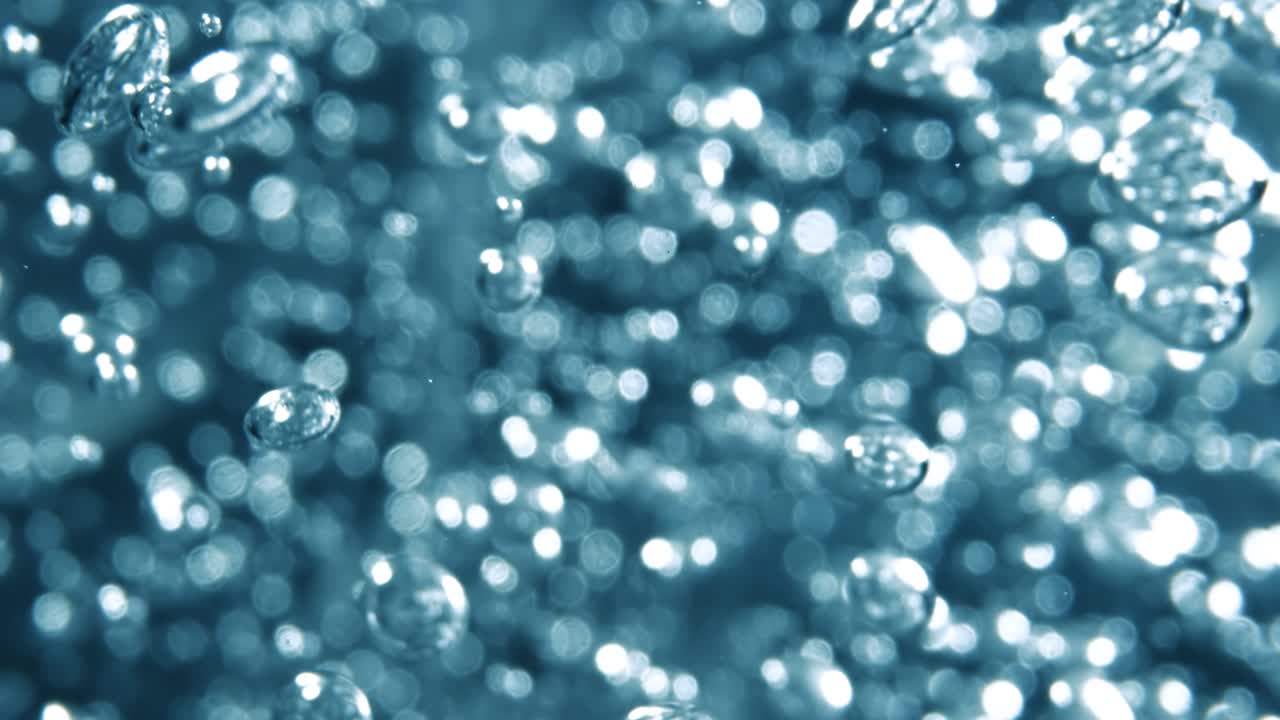Many water bubbles in blue water close up, abstract water wave with bubbles in slow motion.
