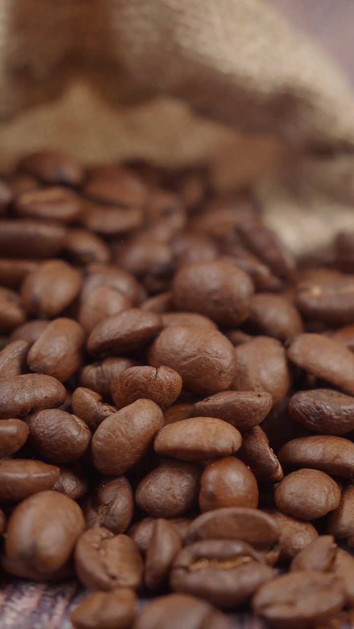 Fagioli di caffè arrostiti che si riversano da un sacco di tela