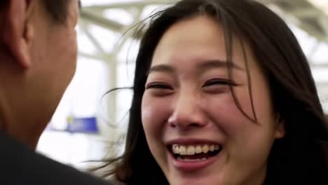a joyful reunion captured in emotion: two individuals embrace with laughter and happiness, celebrating moments of connection and affection at a busy terminal