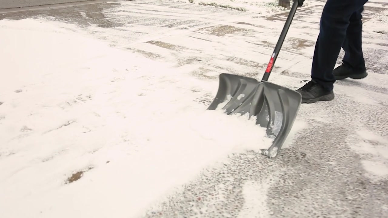 Man shovelling light snow off driveway.
