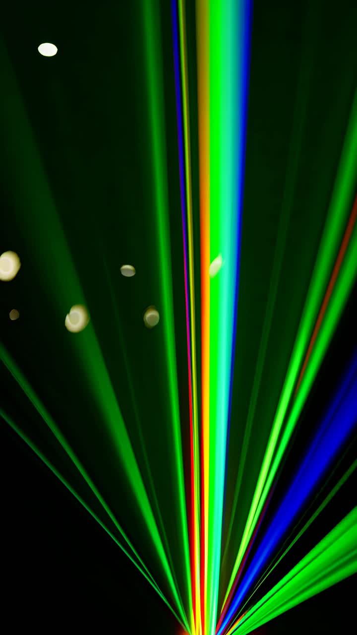 Dynamic video of vibrant blue and green laser beams converging from a low angle