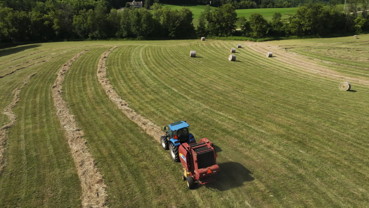 campo lleno de balas de heno redondas con máquina tractora en oronoco, minnesota, ee.uu. - foto aérea