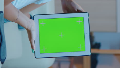 vertical video: young lady holding a tablet with green screen