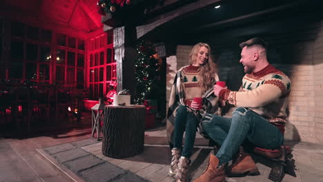 happy young couple in love in christmas sweaters at home. handsome man and beautiful woman sitting in a country house and having joyful time together.
