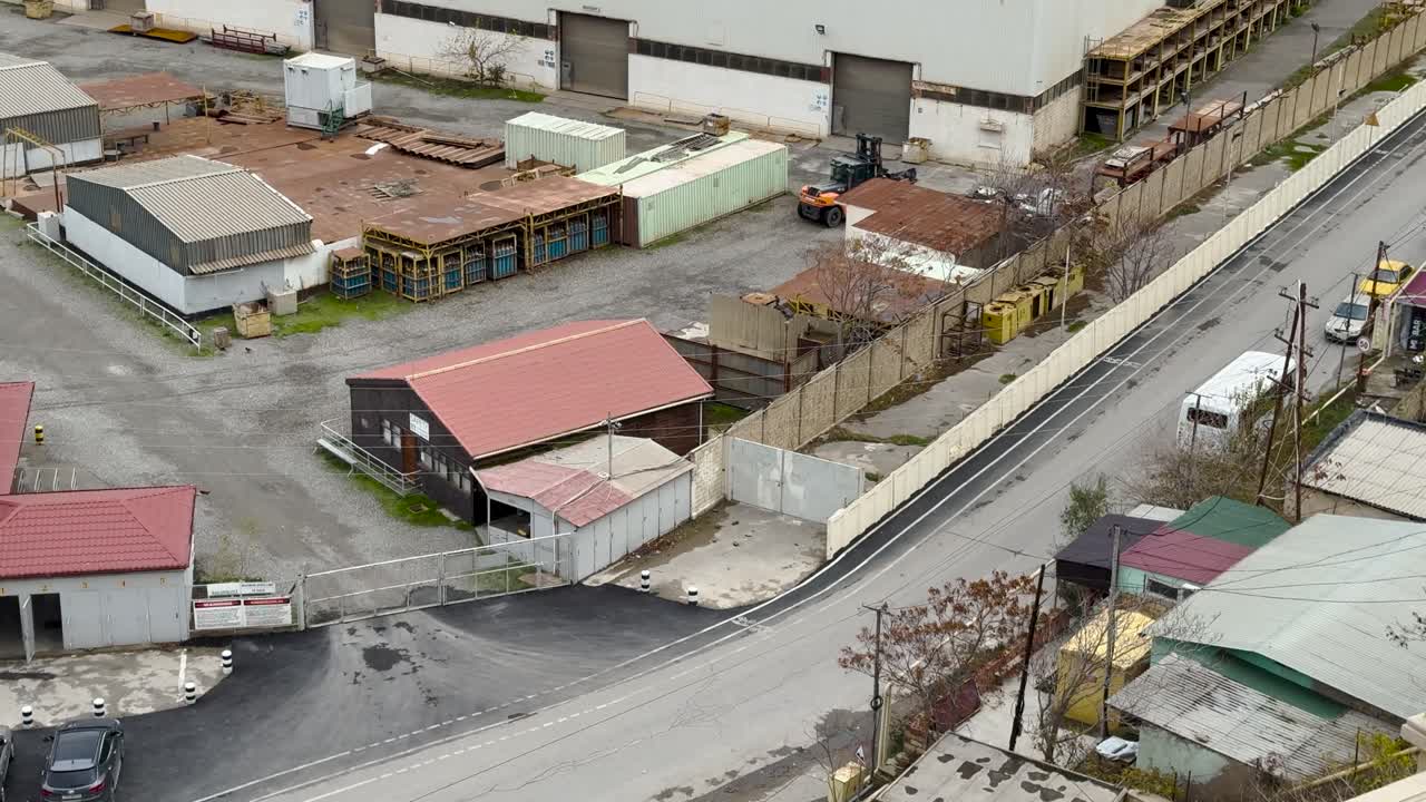 Fixed aerial view of warehouse and containers at industrial area.