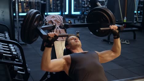 masculine man in 30s doing chest press exercise lifting heavy weight sitted in incline bench press machine at health club